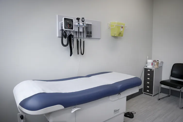 Una sala de reconocimiento médico con una mesa de reconocimiento y herramientas médicas a su alrededor.