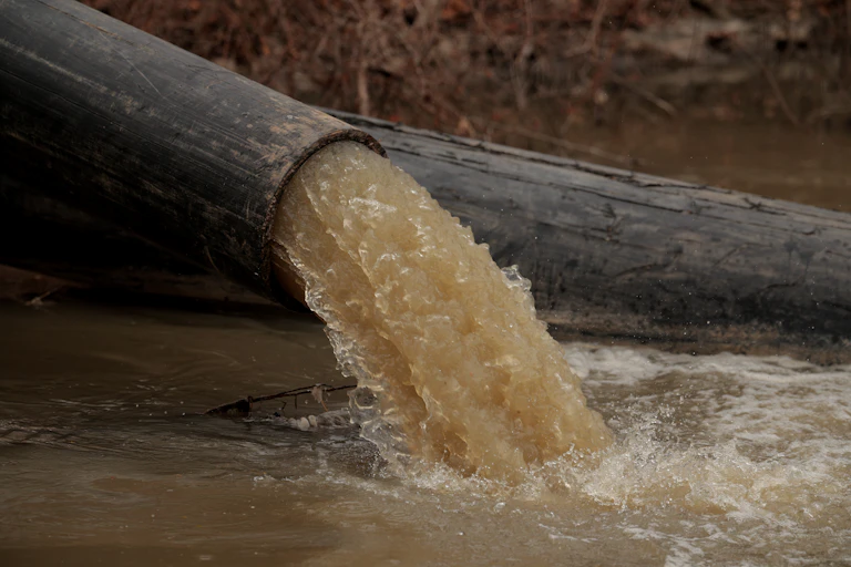 A large pipe spews brown water.