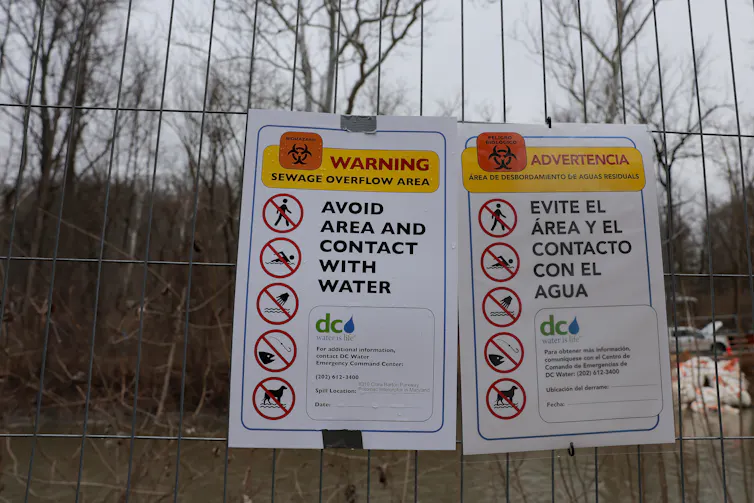 Signs carry warnings in English and Spanish, telling people to stay away from the water, which is contaminated with sewage.