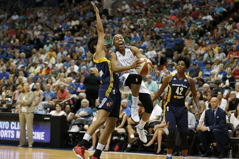 Two WNBA Indiana Fever guards, Layshia Clarendon and Shenise Johnson, try to stop Minnesota Lynx guard Renee Montgomery from scoring at a WNBA basketball game.