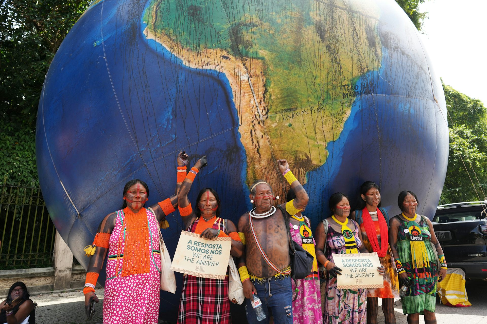 La gente posa para una foto frente a un modelo de globo terráqueo gigante.