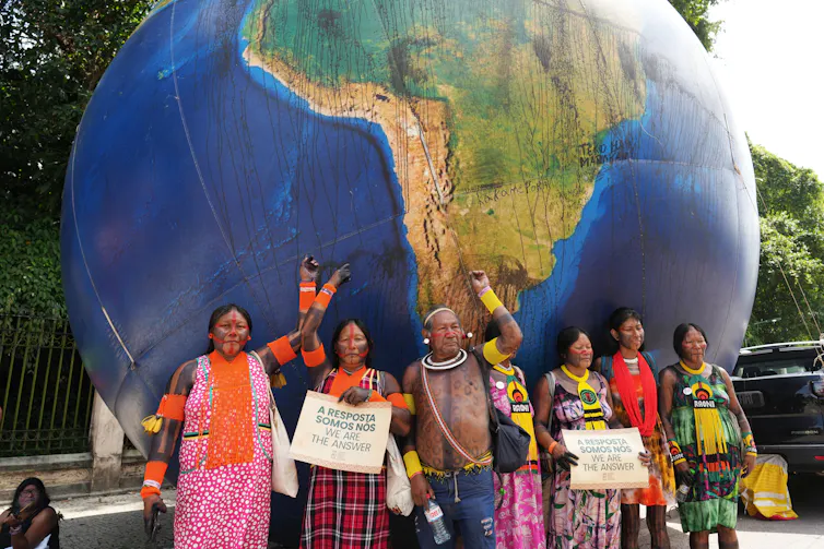 People pose for a photo in front of a giant model of a globe