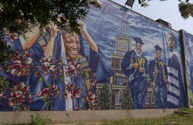 Mural showing many Black graduates in robes and caps at a celebration.