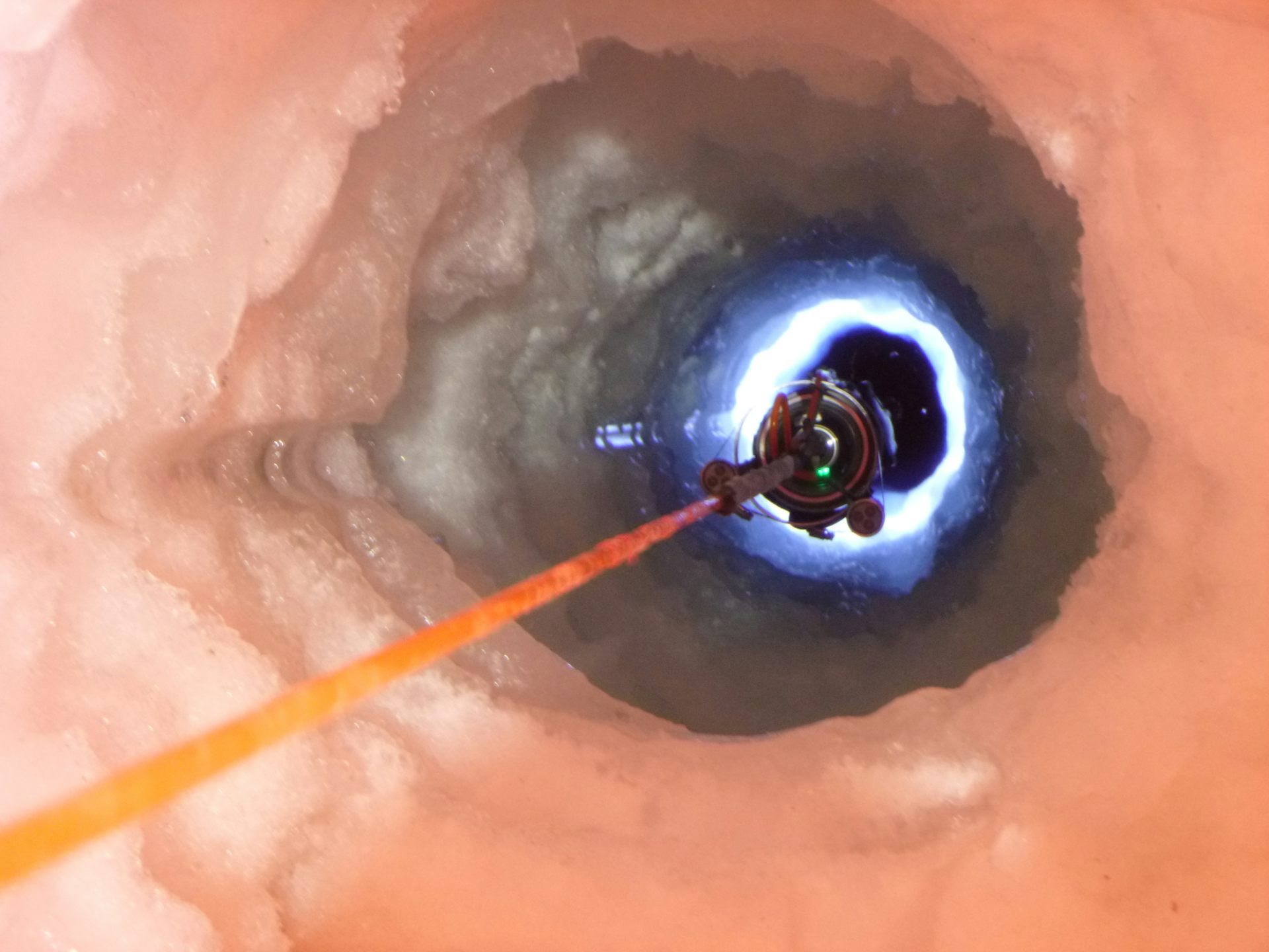 Looking down a narrow ice borehole as instruments are lowered.