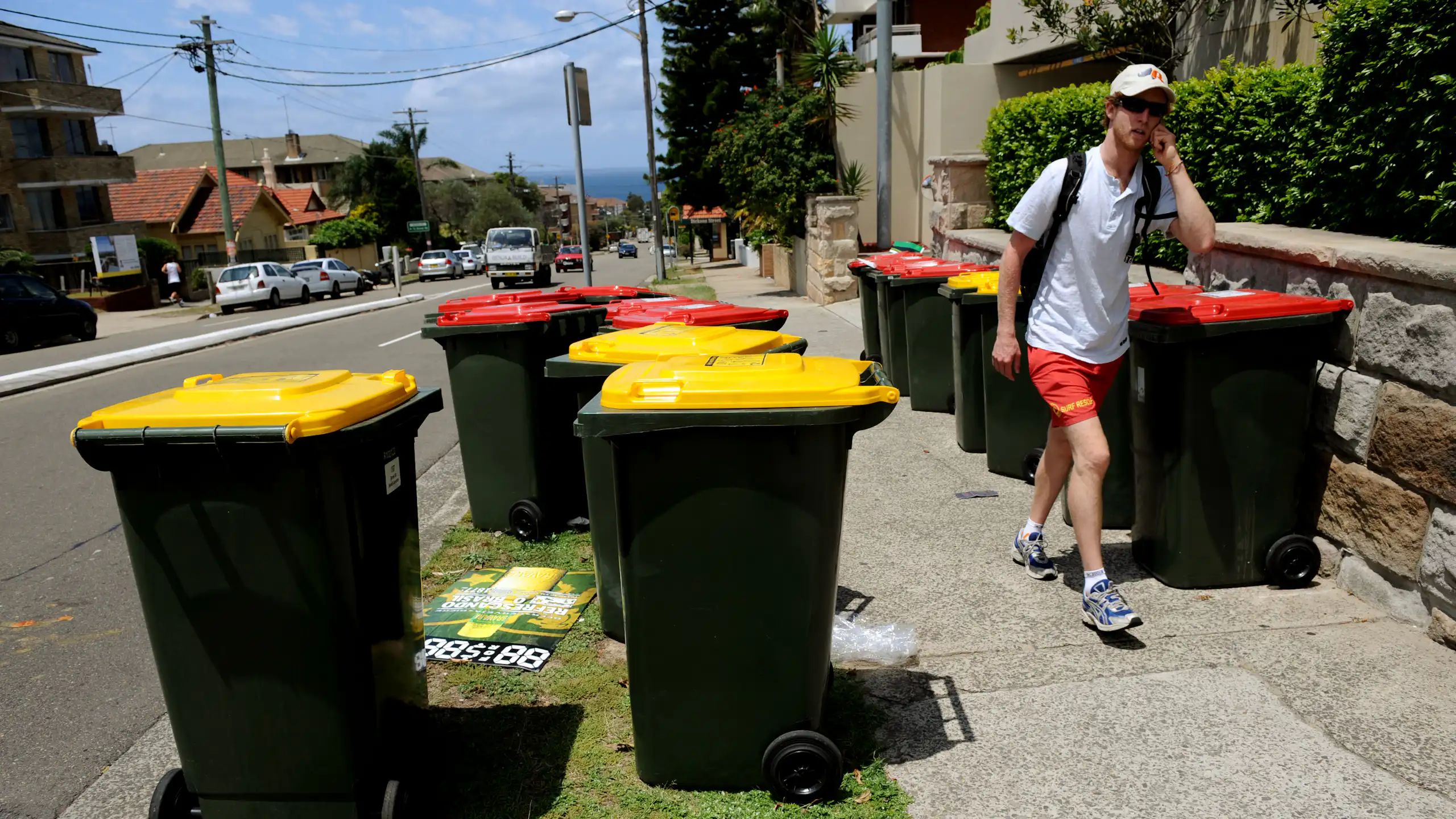 A man walks past some recycling bins