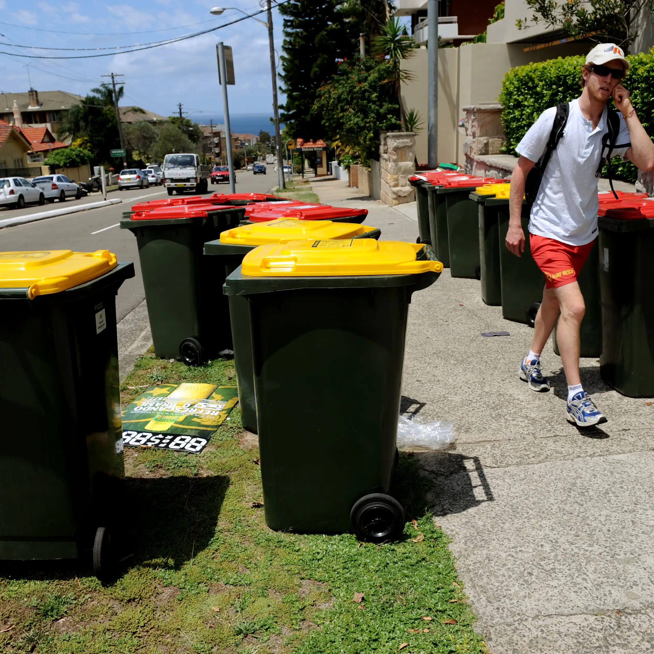 A man walks past some recycling bins