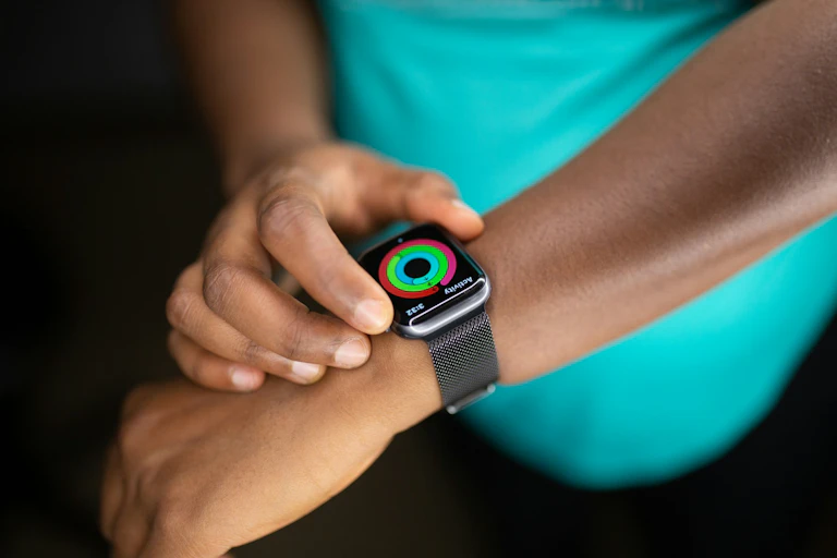 Person wearing teal T-shirt, adjusting smartwatch
