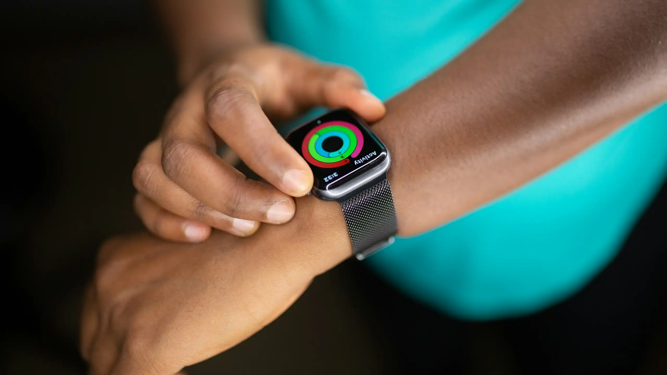 Person wearing teal T-shirt, adjusting smartwatch