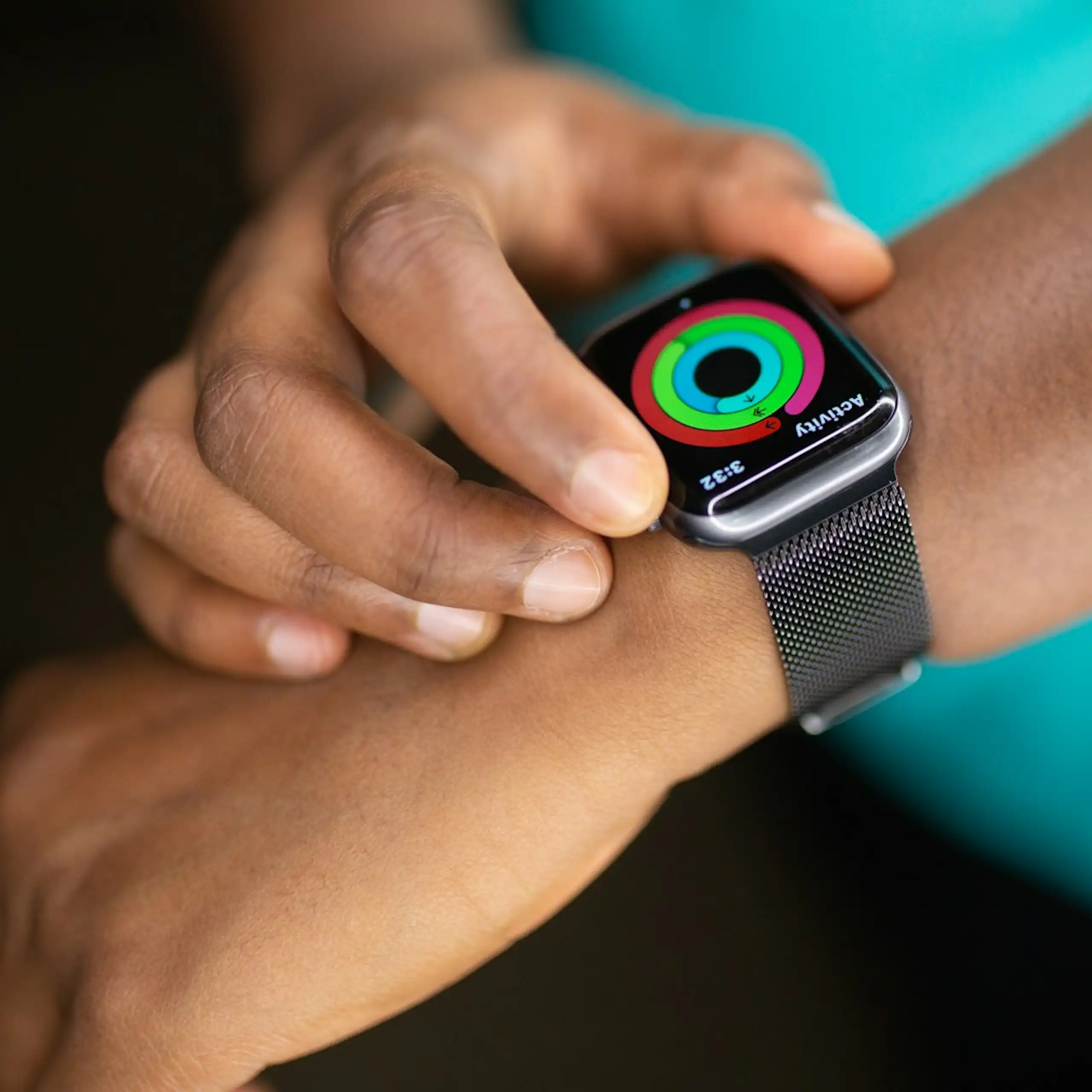 Person wearing teal T-shirt, adjusting smartwatch