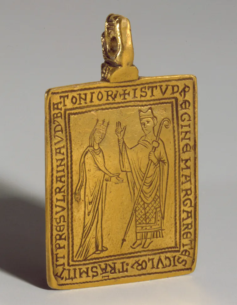 A gold pendant with Latin writing.
