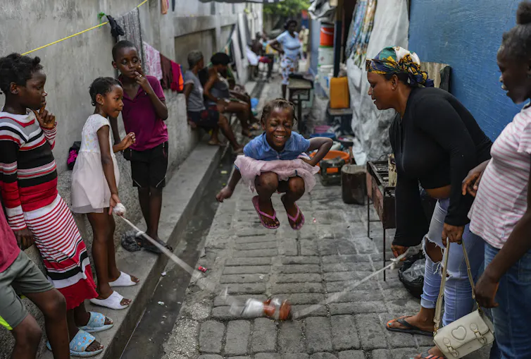 A young girl skips rope in a small alley.
