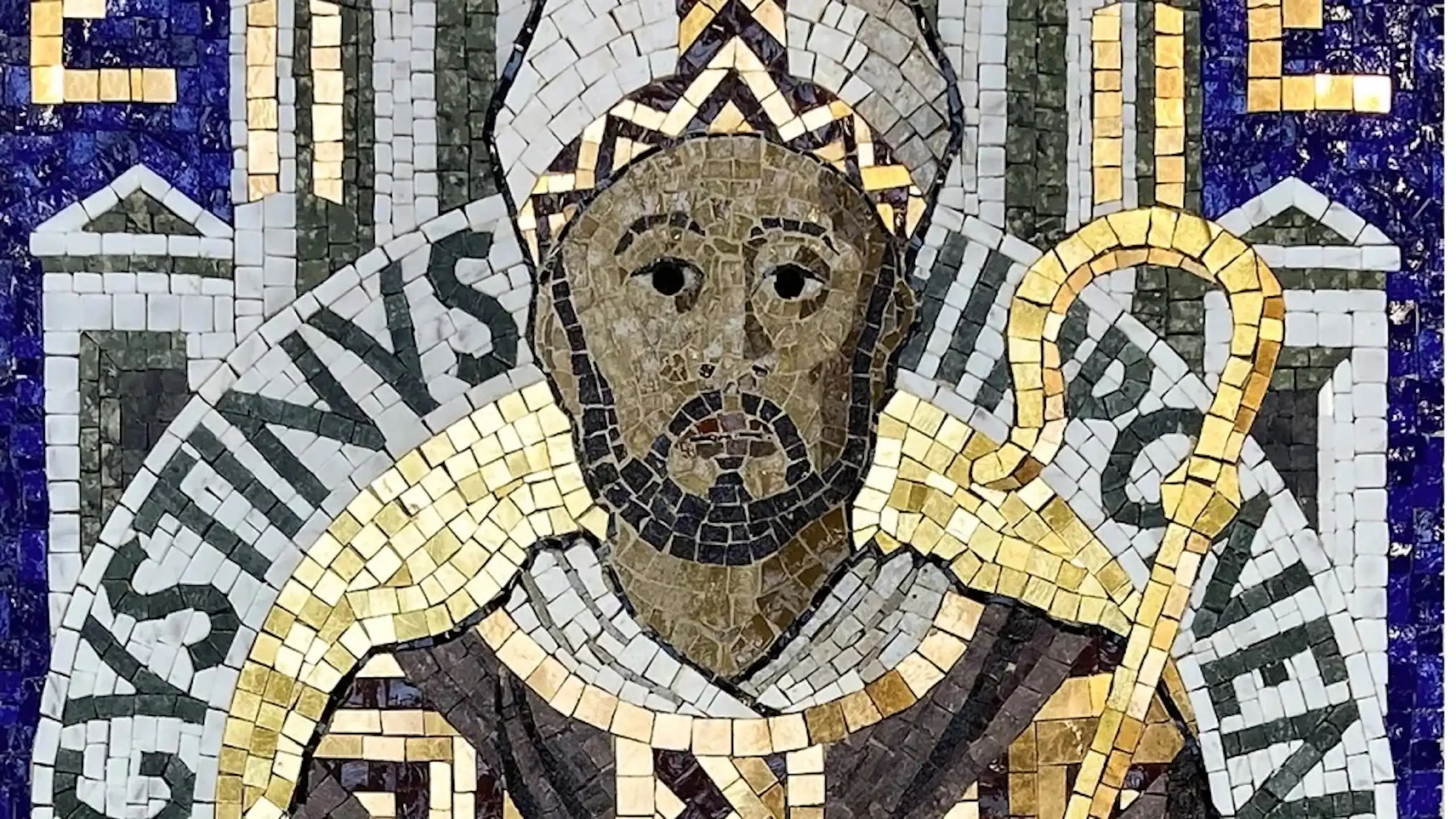 A mosaic artwork of a dark-skinned man in a bishop's headgear holding a staff.