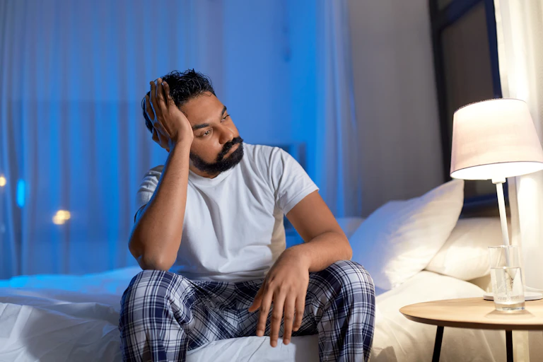 Man sits on bed with frustrated expression