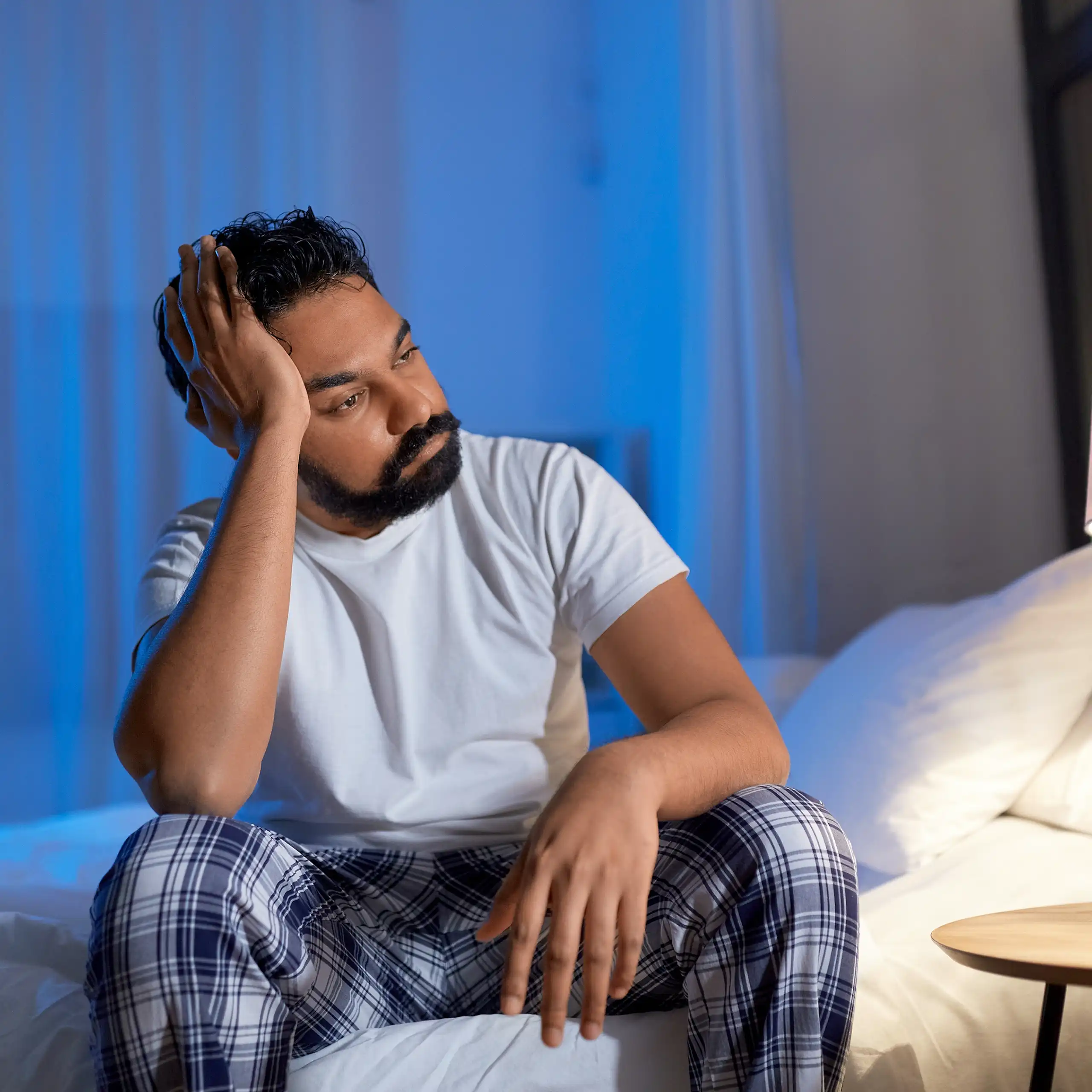 Man sits on bed with frustrated expression