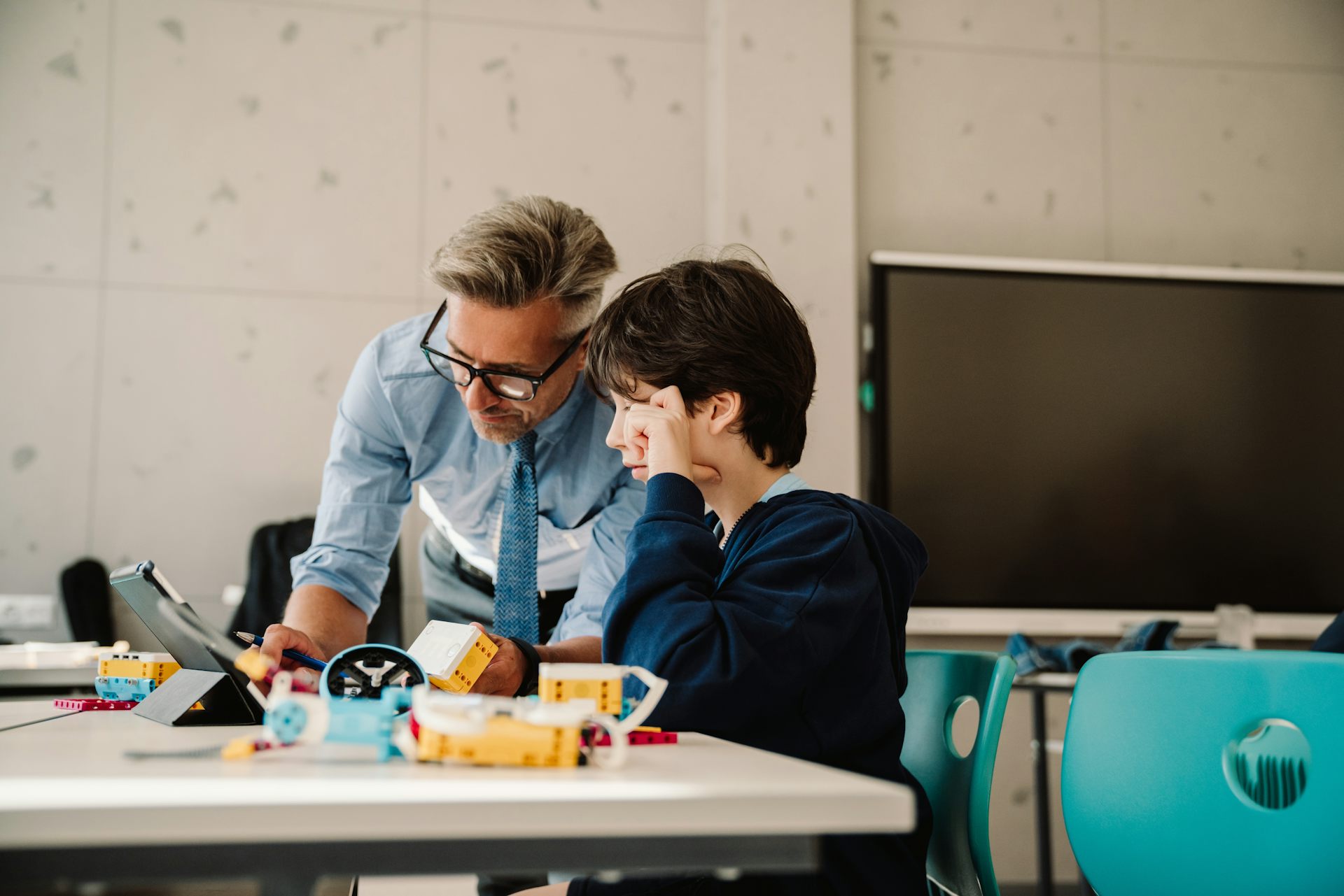 Male teacher helping a boy with schoolwork.
