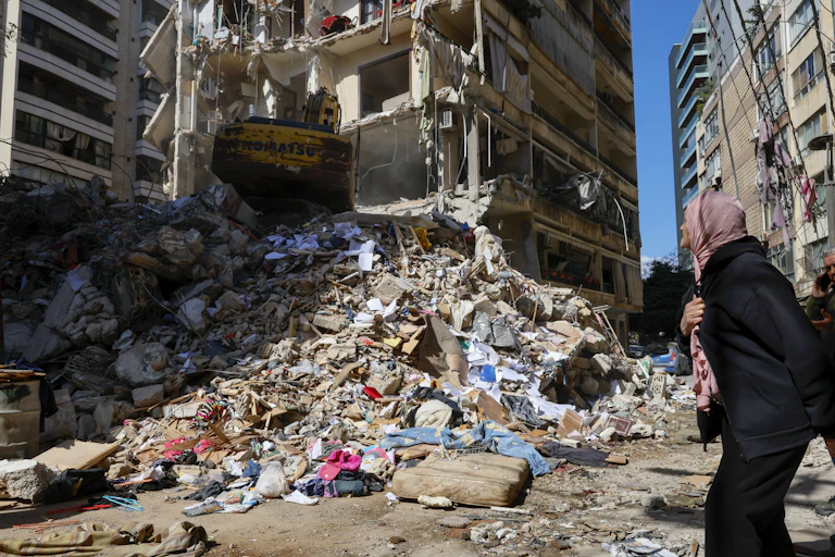 A woman watches as a bulldozer clears the rubble of a destroyed building the day after an Israeli airstrike in the Ain Mreisseh neighborhood of Beirut, Lebanon