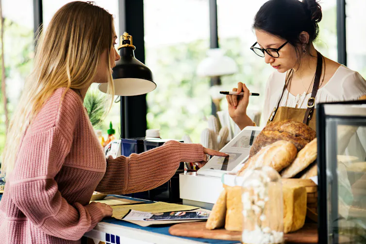 A woman is paying a cashier for her purchases at a bakery.