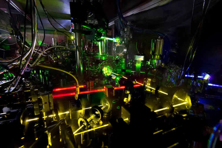 Uma grande máquina na escuridão, com lasers ópticos brilhantes atravessando-a