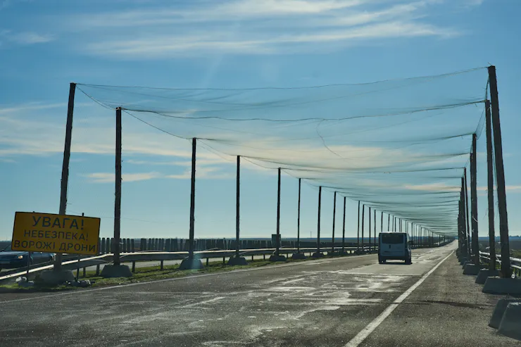 a road lined with poles on both sides supporting netting over the road