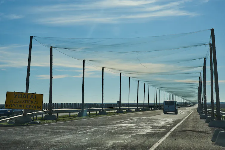 a road lined with poles on both sides supporting netting over the road