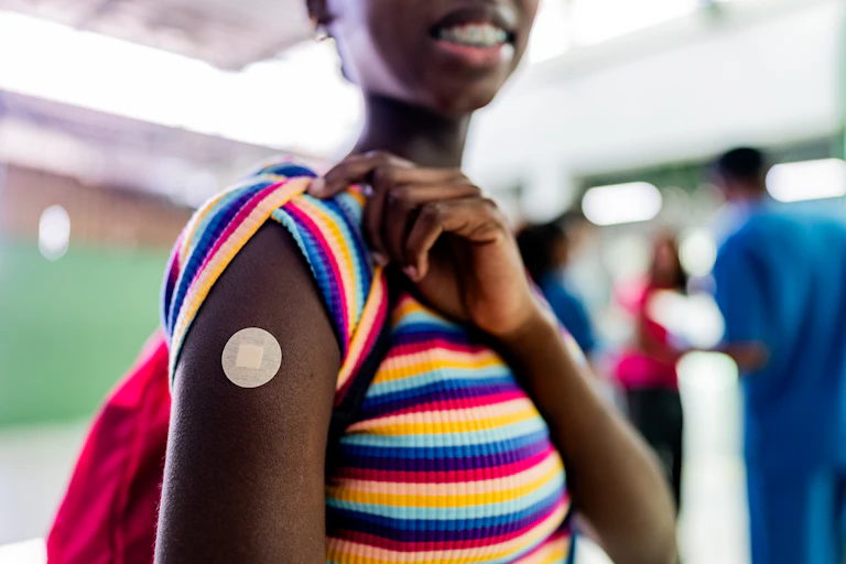 Teen girl shows band-aid on her bicep.