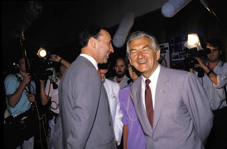 Paul Keating and Bob Hawke laughing in front of the media in the 1980s