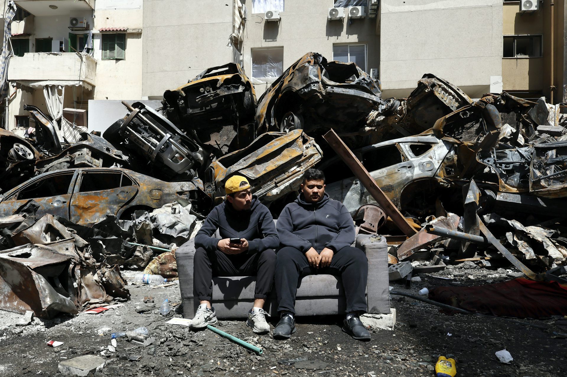 two young men on a couch in front of rubble