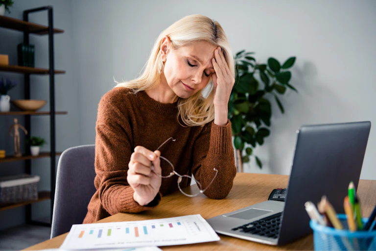 Middle aged businesswoman with blonde hair suffering from a headache