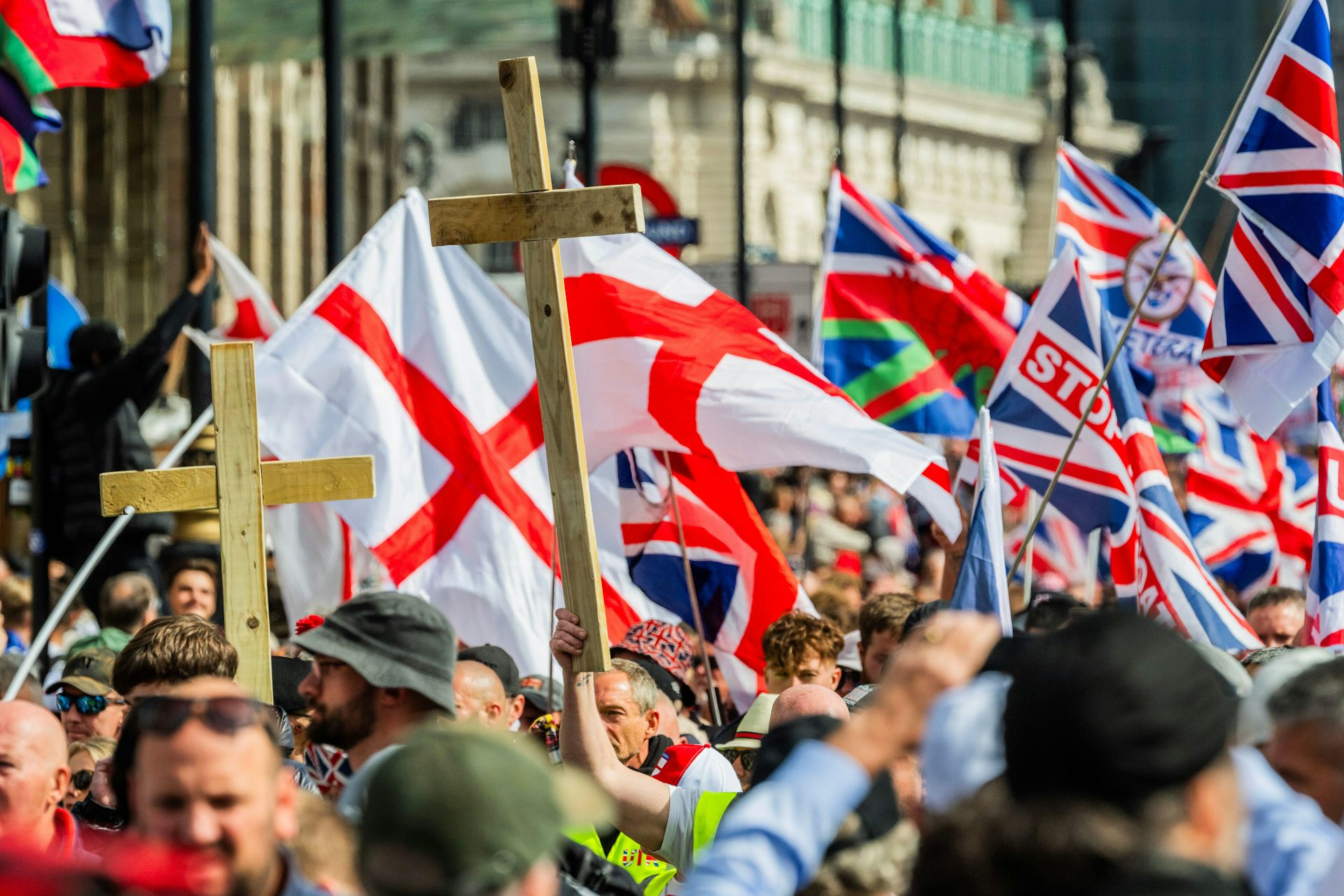 Marchers carrying UK and England flags, and large wooden crosses
