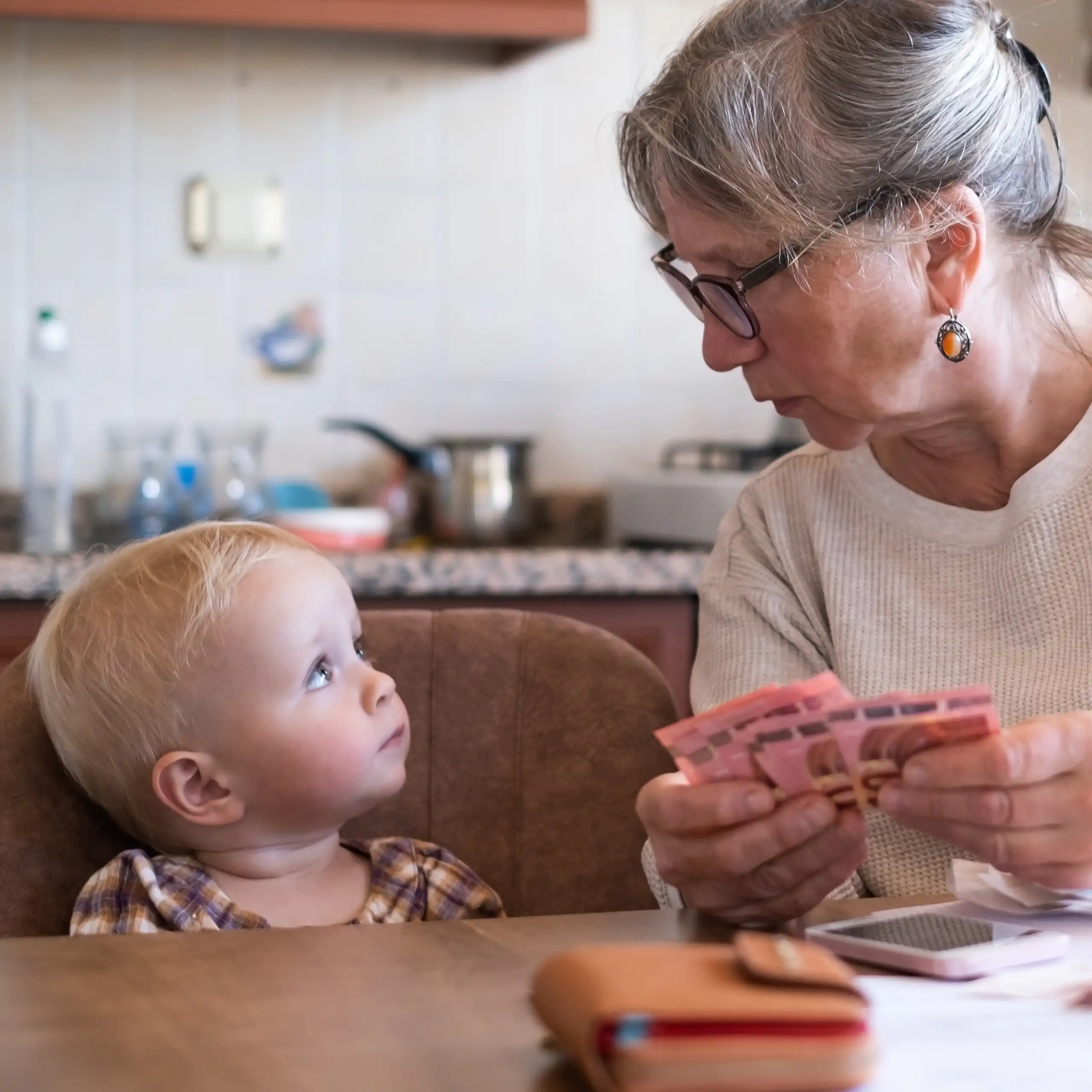 Femme tenant de l'argent à côté d'une petite fille.