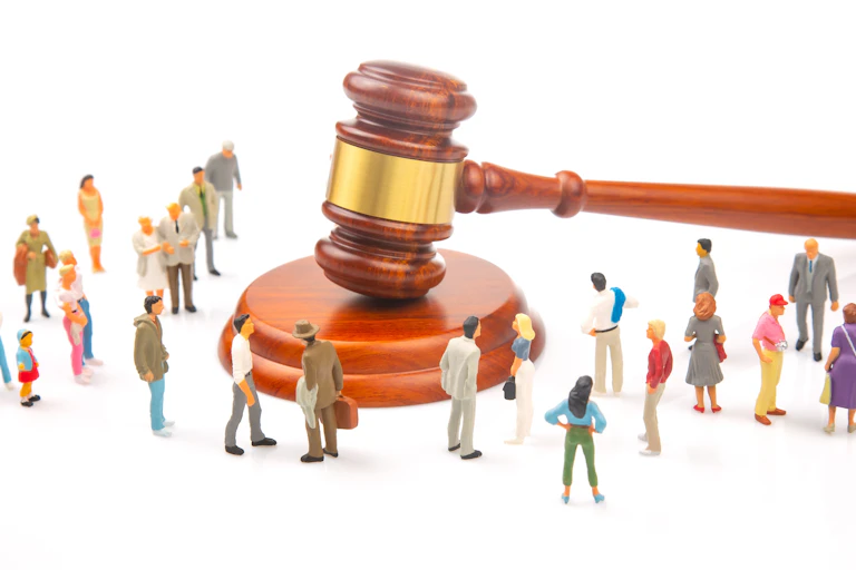 Création : un marteau de justice et des figurines d'êtres humains de taille très inférieure au marteau.