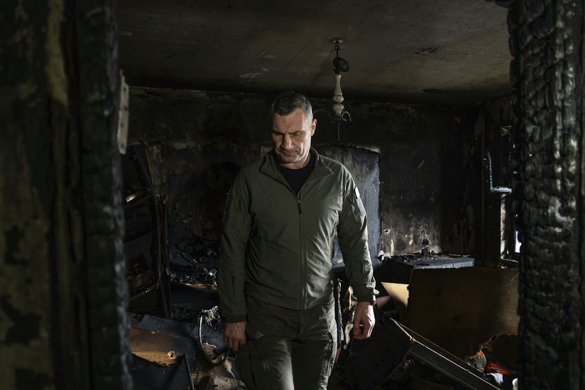 A man walks through a burned out apartment.