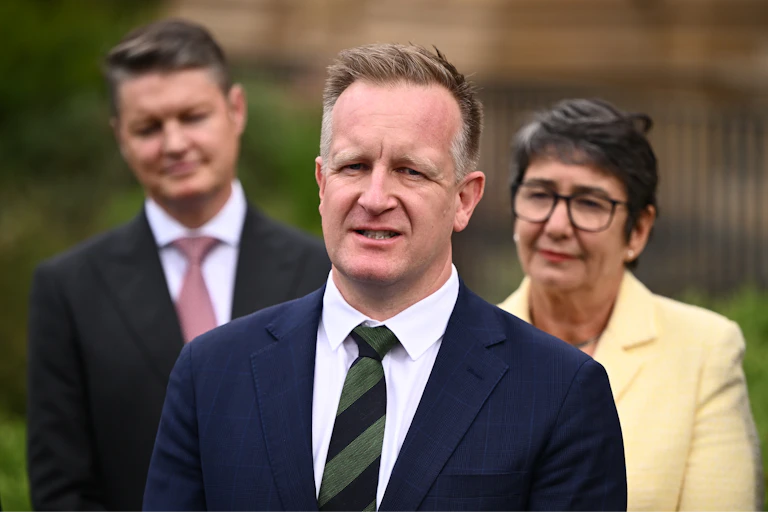 A man in a suit speaks outside in front of his colleagues