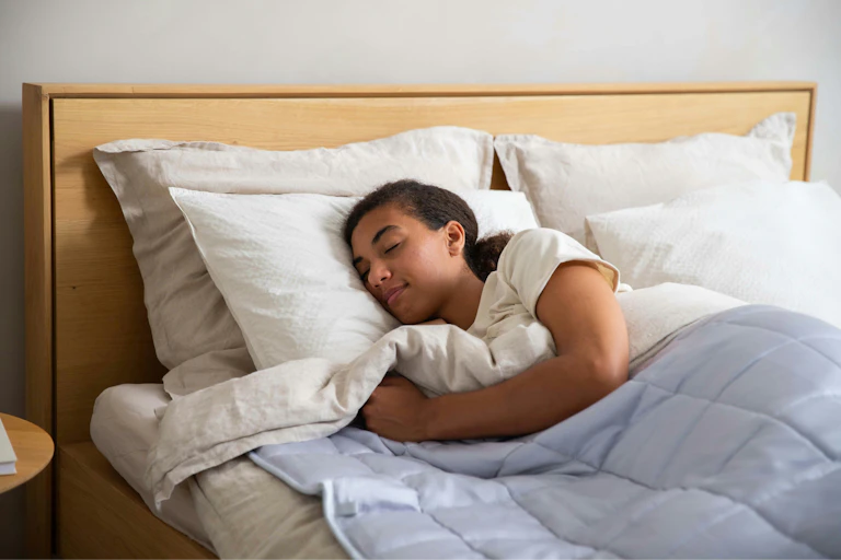 Young woman sleeps soundly in a double bed.