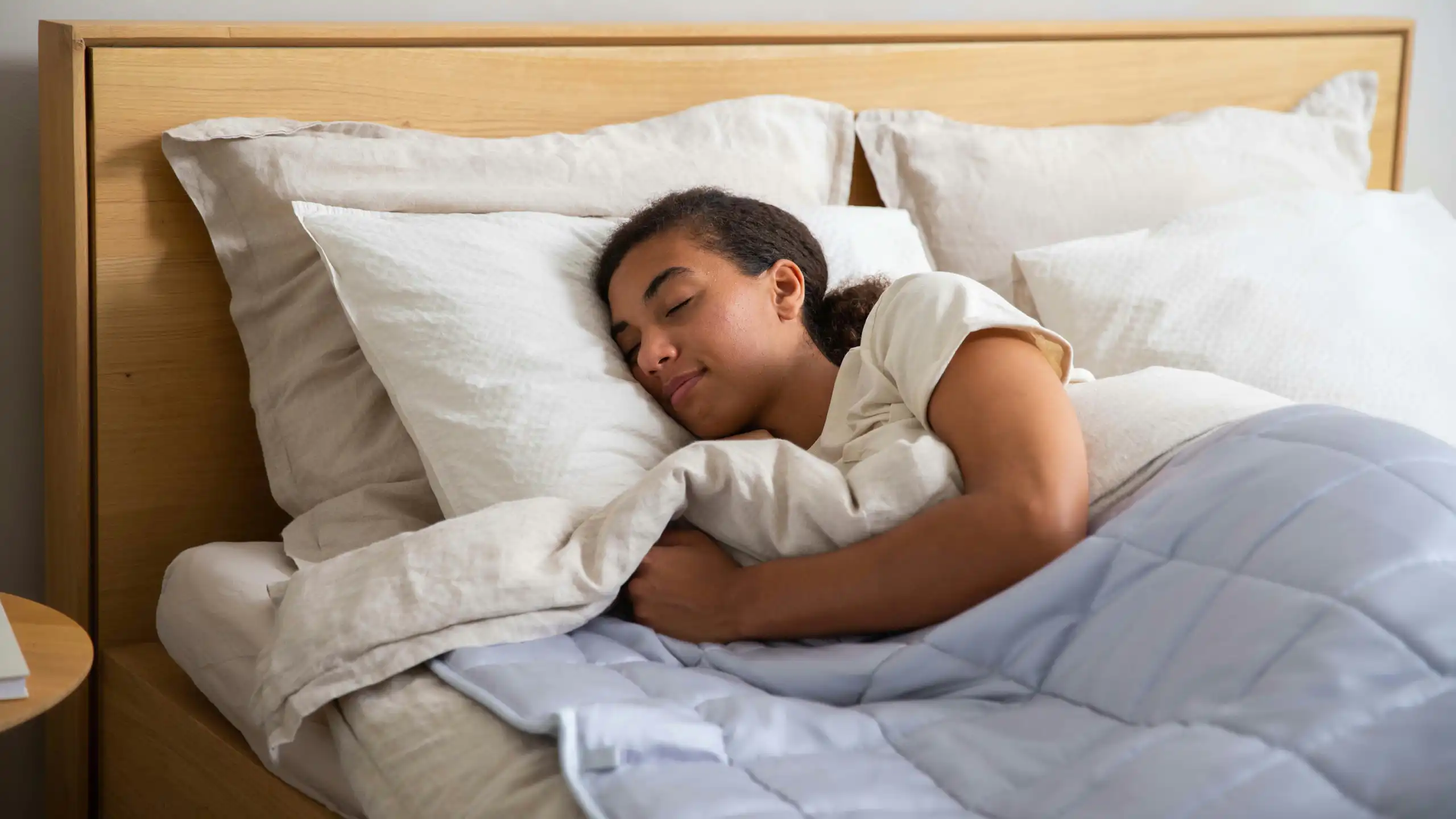 Young woman sleeps soundly in a double bed.