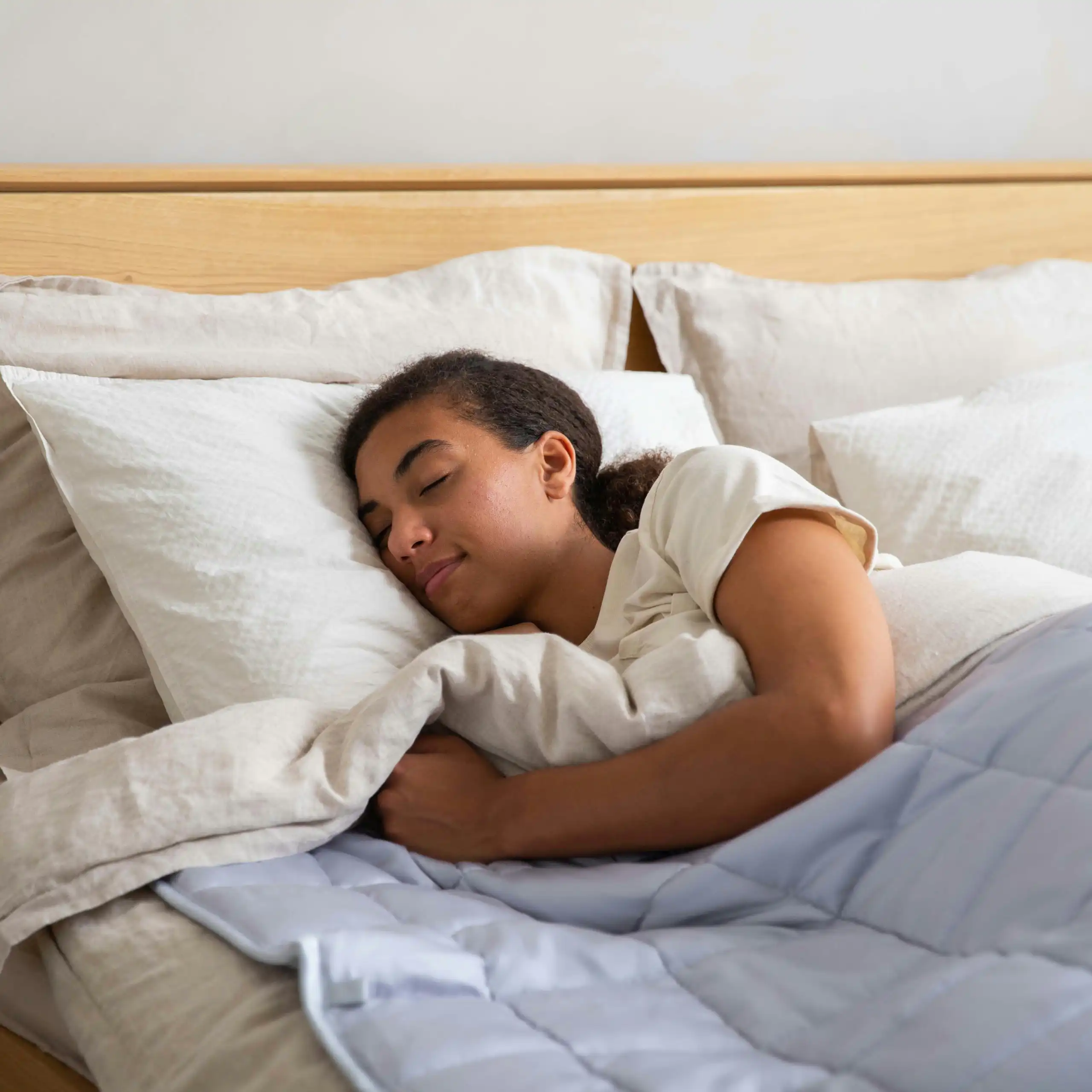 Young woman sleeps soundly in a double bed.