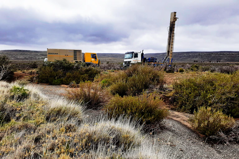 Indigenous shrubs and grasses with a borehole drilling machine behind them
