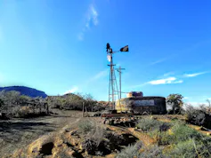 A remote place with only a few shrubs, a small reservoir and two windmills powering the borehole.