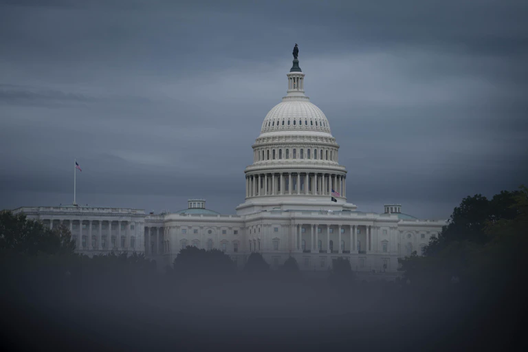 A large white building with a dome, fading behind clouds.