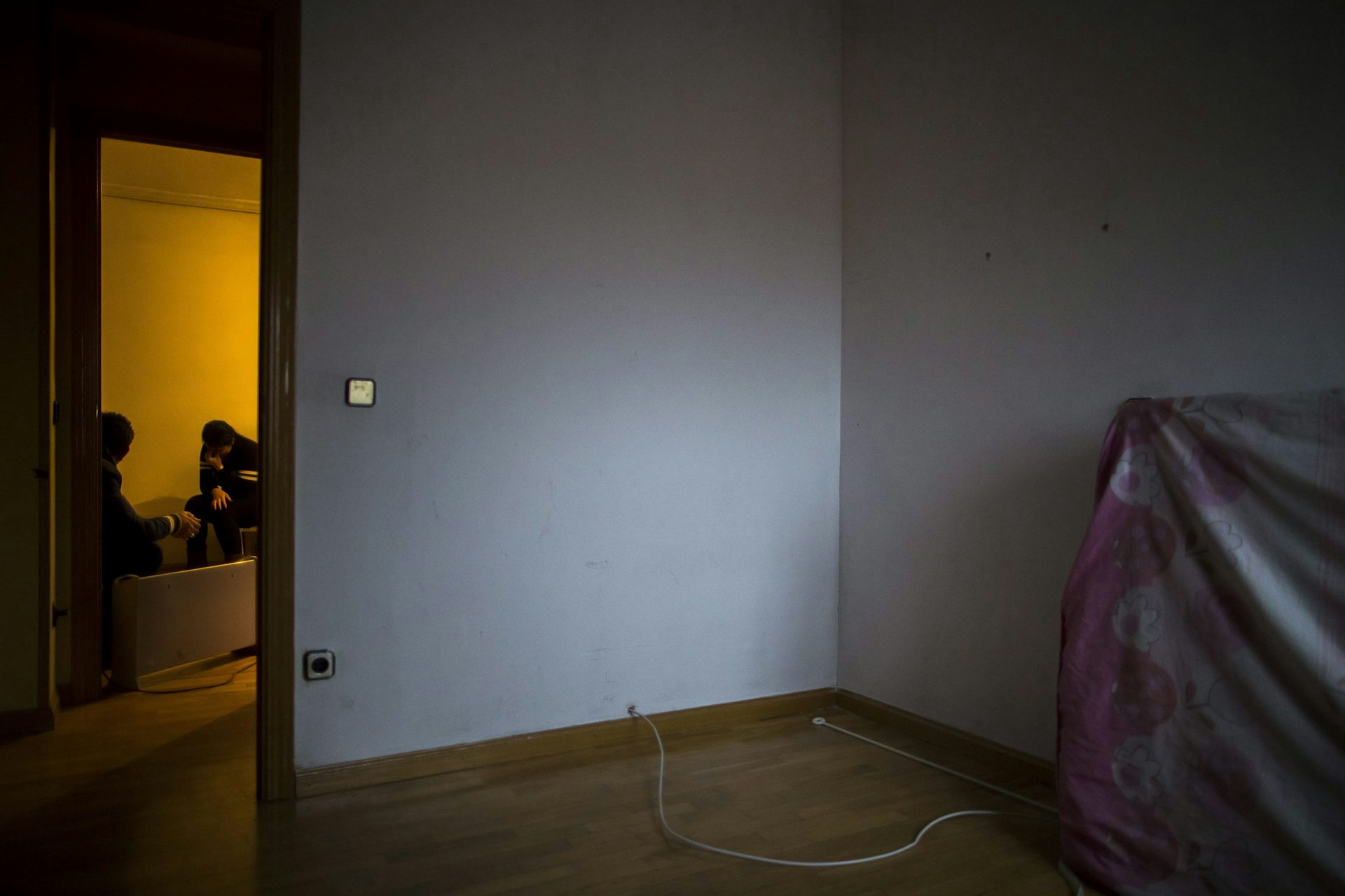 Une femme apparait d&eacute;sesp&eacute;r&eacute;e dans le cadre de porte d'une pi&egrave;ce vide &agrave; l'exception d'un matelas adoss&eacute; au mur