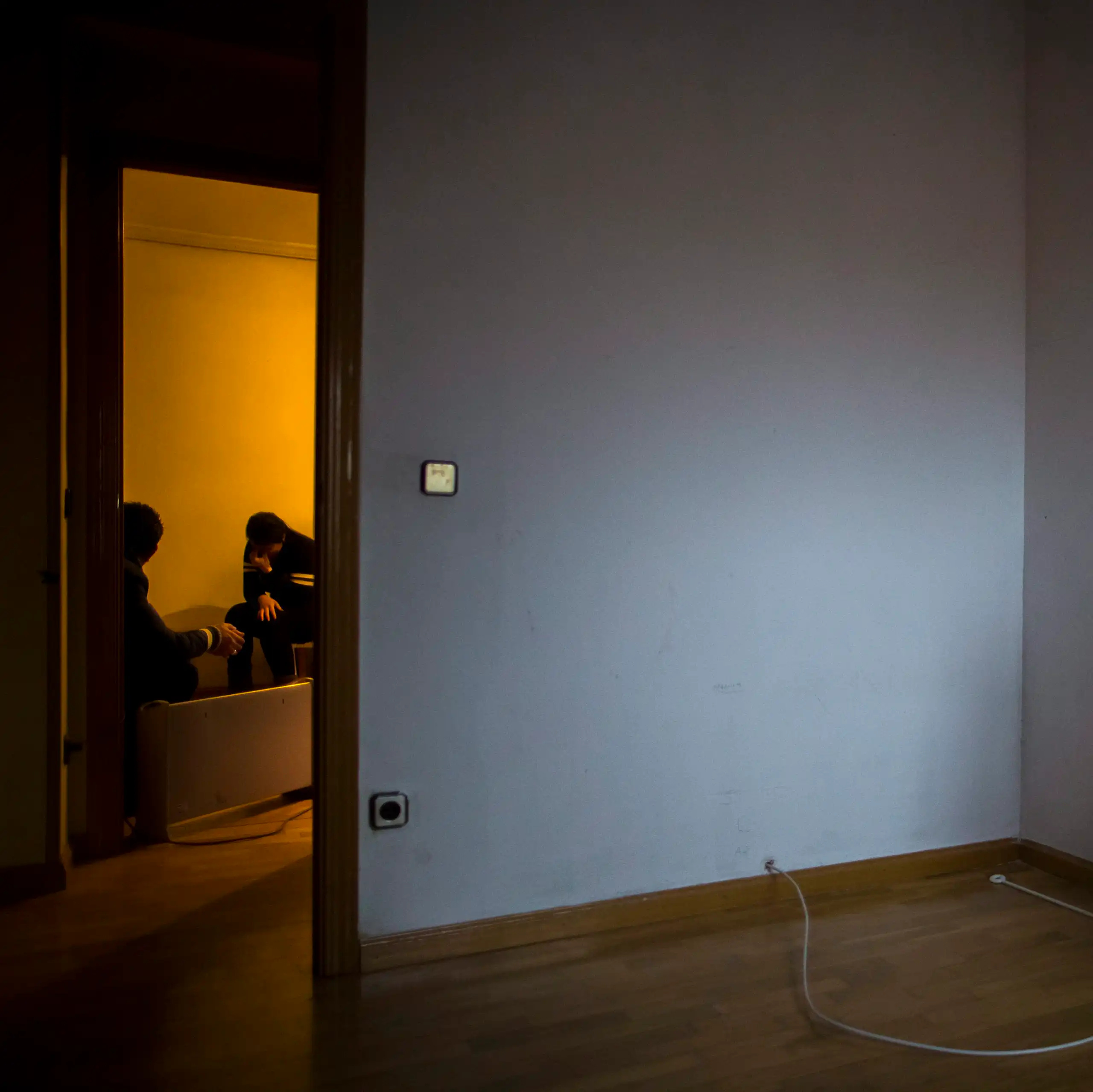 Une femme apparait désespérée dans le cadre de porte d'une pièce vide à l'exception d'un matelas adossé au mur