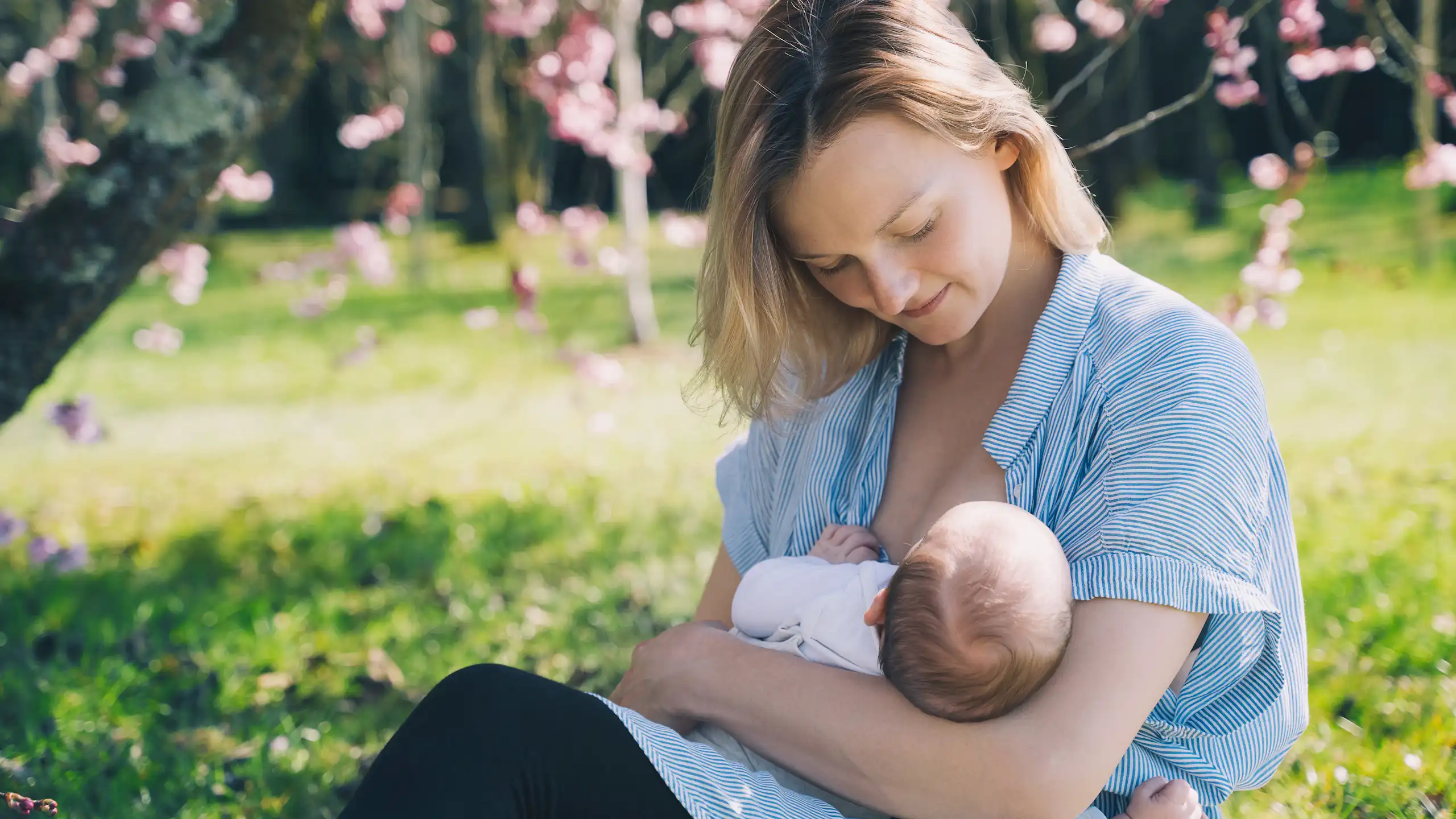 Une femme allaite son bébé dans un environnement champêtre.