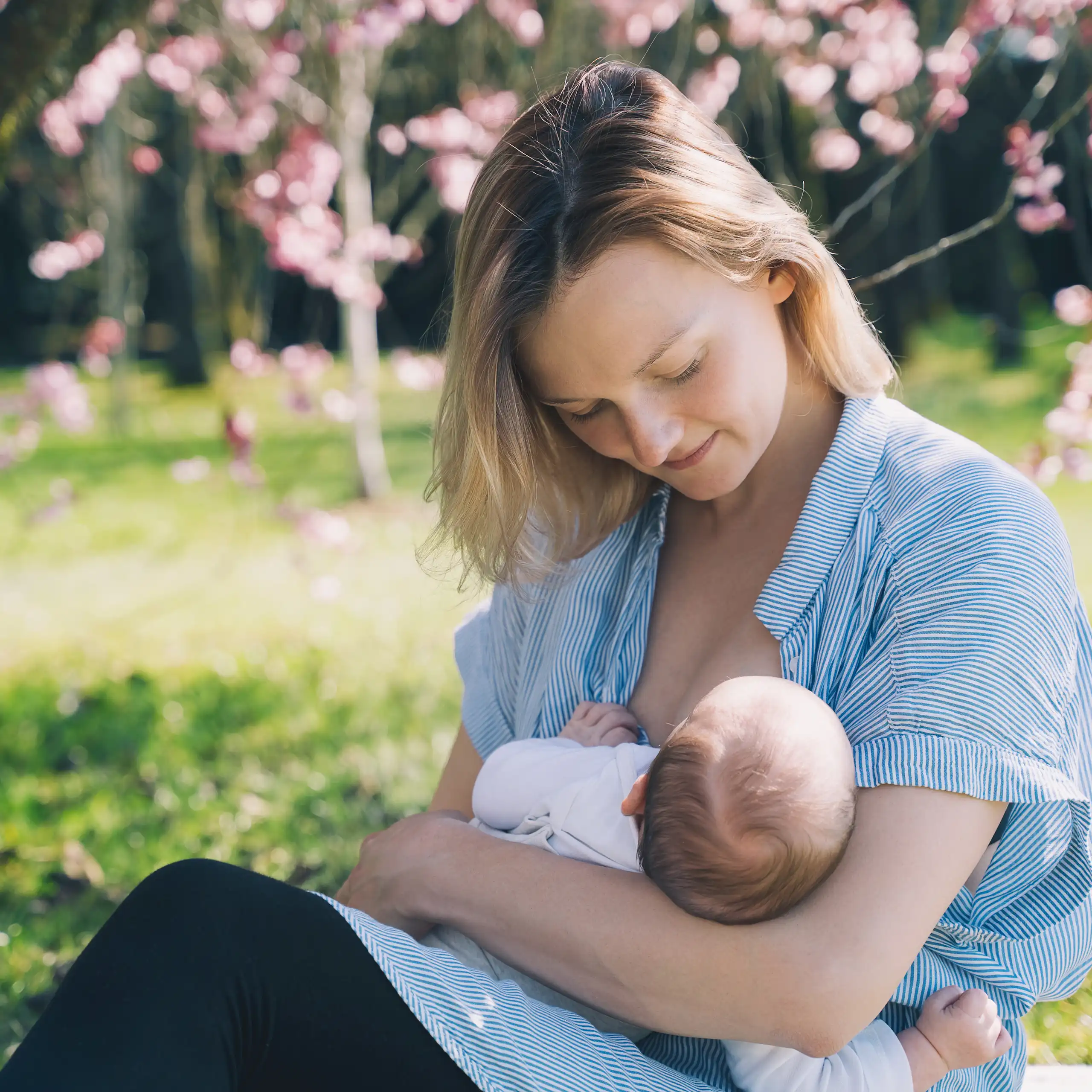 Une femme allaite son bébé dans un environnement champêtre.