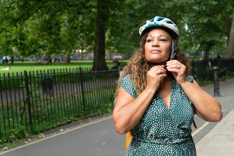 A woman puts on a bike helmet.