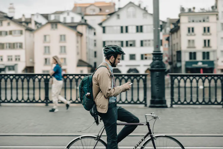 A man looks at his phone while on his bike.