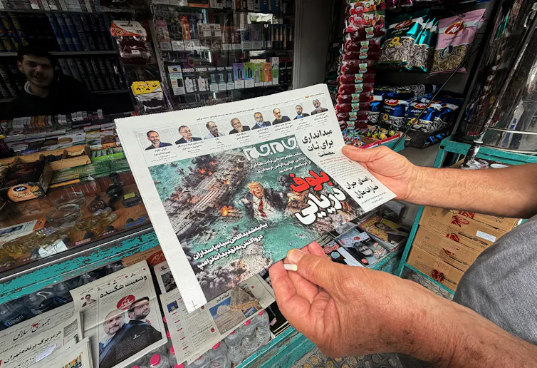 A man looks at the front page of the Jam Jam newspaper on sale at a newsstand, featuring a cartoon of US President Donald Trump drowning in the Strait of Hormuz with the headline 'Marine Bluff,' in Tehran
