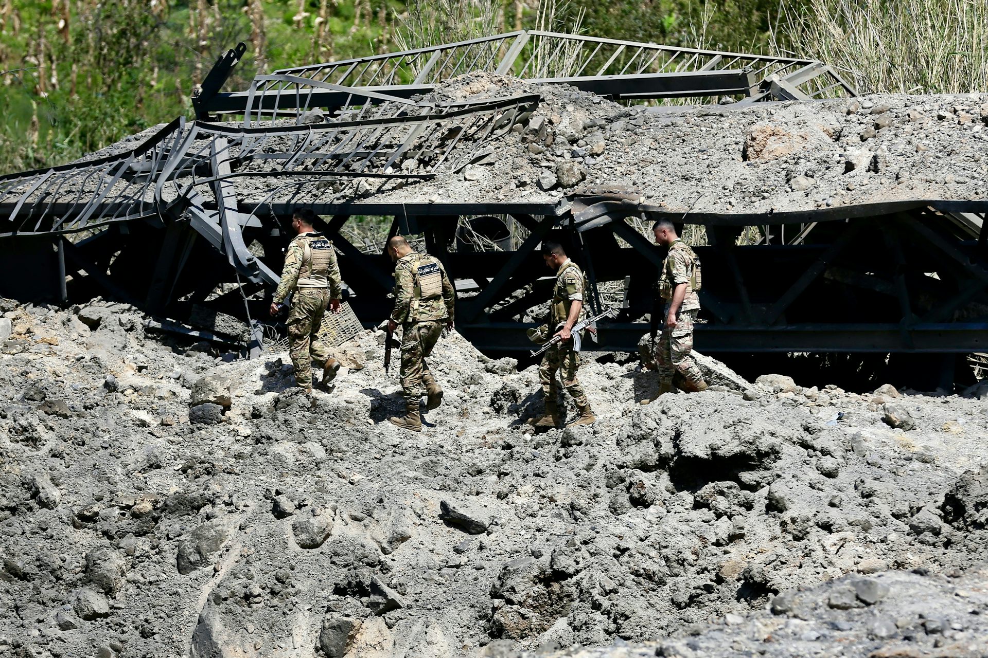 Lebanese army soldiers cross over a damaged bridge.