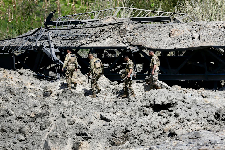 Lebanese army soldiers cross over a damaged bridge.