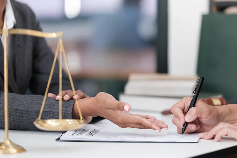 stock photo of a lawyer speaking to client at desk, with scales of justice on the desk