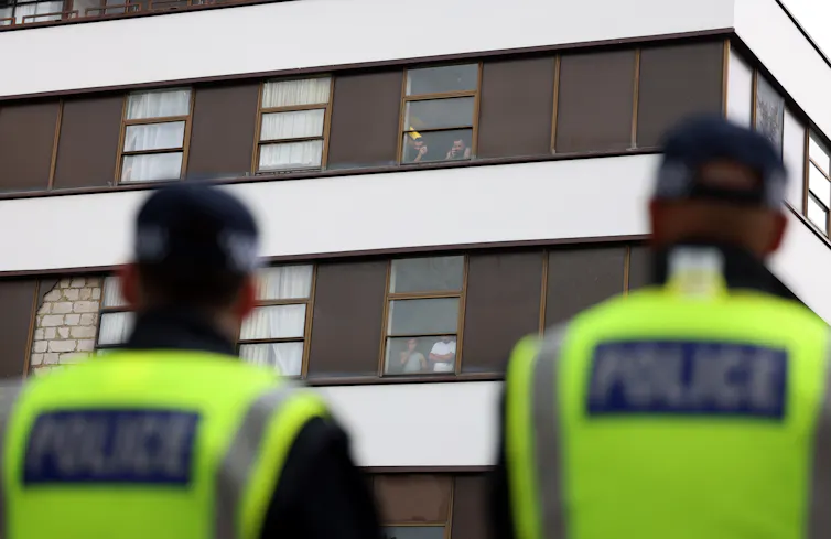 two police officers looking up at an asylum hotel